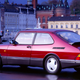 A photo of a red Saab 900 Turbo parked in a city.